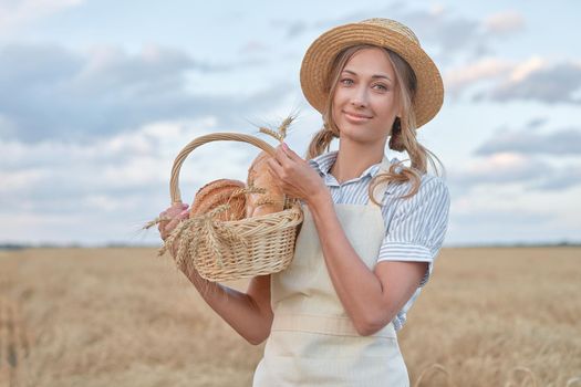 Female farmer standing wheat agricultural field Woman baker holding wicker basket bread eco product Baking small business Caucasian person dressed straw hat apron organic healthy food concept