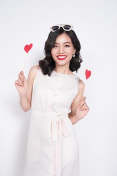 Fashionable woman in nice dresses holding red heart shape.