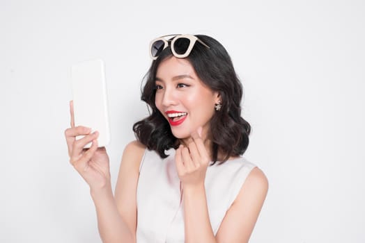 Portrait of a smiling cute woman making selfie photo on smartphone isolated on a white background