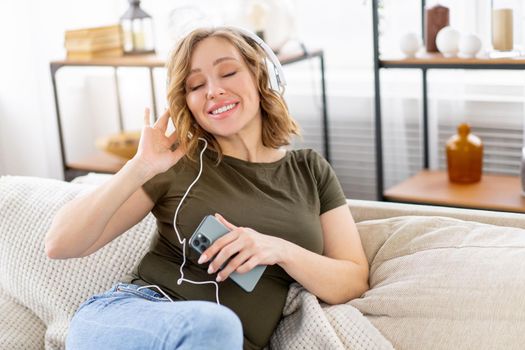 Pregnant woman listen music headphones lying on the couch holding smartphone in hand Relax enjoy atmospere