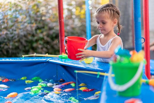 Child Fisher Catching Plastic Toy Fish On Pool Amusement Park Summer Day Little Girl Have Fun On Fishing Carnival Festival Entertainment For Children