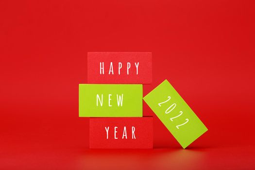 Happy New Year red minimal trendy concept. Modern composition with red toy blocks with written Happy New Year 2022 text against red background with copy space. Minimalistic postcard