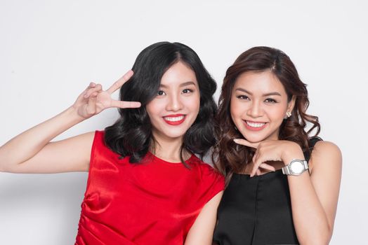 Two fashionable women in nice dresses standing together and having fun