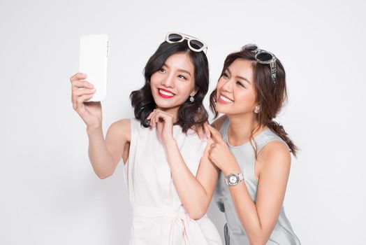 Portrait of two beautiful asian fashionable women taking selfie