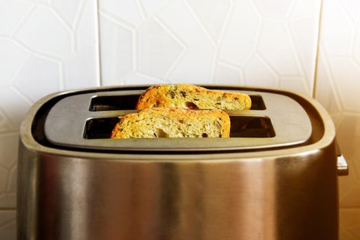 two slices of fried toast sticking out of a stainless toaster.