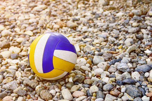 Close up of colored volleyball ball on a sea pebble beach. Summer beach games.