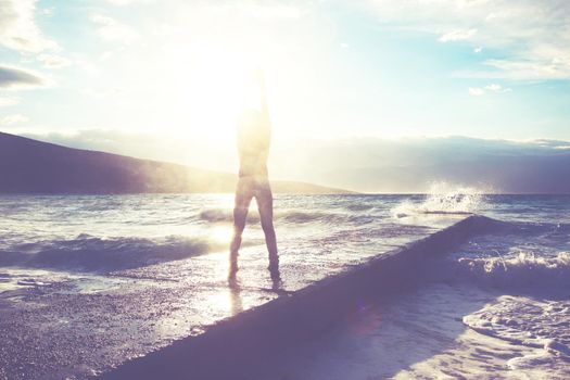 Feeling of freedom concept. Woman jump on pier facing to the sea with big waves.