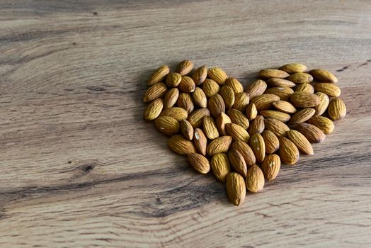 Almonds lying on the table in the form of a heart. Copy space.