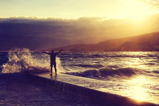 Feeling of freedom concept. Man standing on pier facing to the sea with big waves.