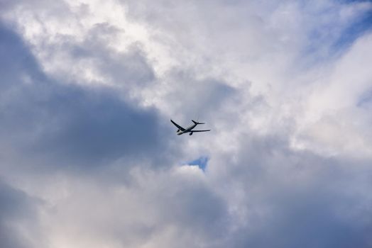 Passenger airplane is flying far away against the sky with clouds.