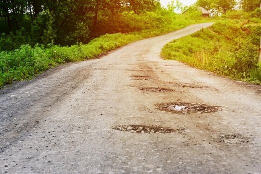 Village life, empty bad dirt road to country houses with sunlight.