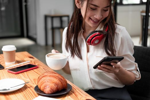 Asian woman wearing headphone while using of smart phonefor online meeting video call.