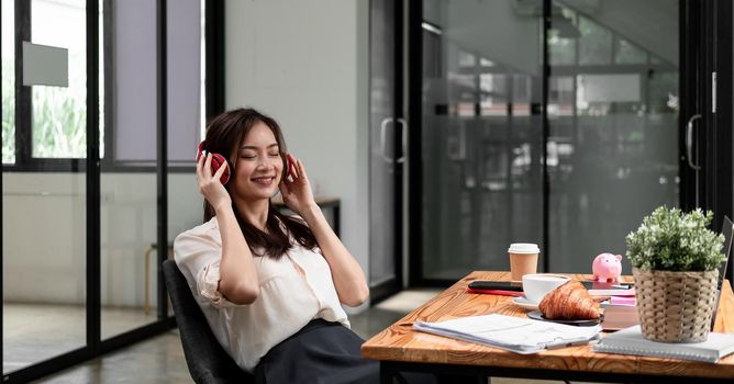 Relaxing moment with music, Businesswoman wearing headphone listening the music during calculate financial accounting, money saveing caoncept .