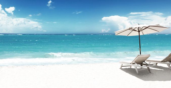 Wooden deck chairs on sandy beach near sea. Holiday background.