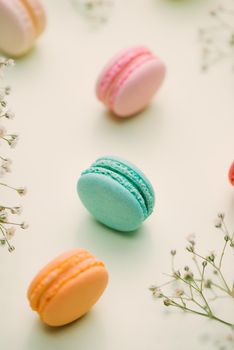 Morning cake macaron and flower gypsophila on light green background from above. Cozy breakfast. Flat lay style.