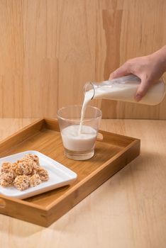 Milk with almond candies on a wooden table