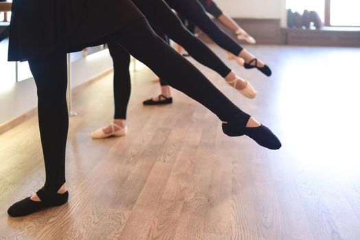 low section of The elegant legs of ballet dancers standing in a row perform stretching exercises