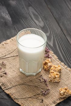 Milk with almond candies on a wooden table