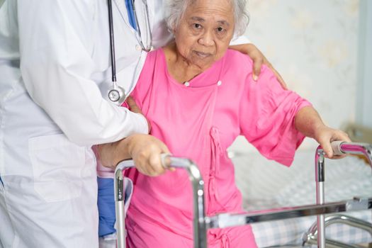Asian nurse physiotherapist doctor care, help and support senior or elderly old lady woman patient walk with walker at hospital ward, healthy strong medical concept.