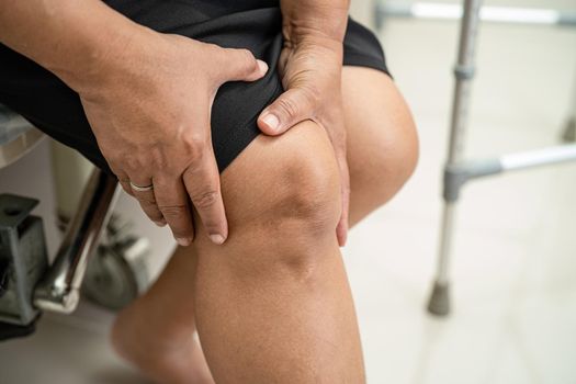Asian middle-aged lady woman patient touch and feel pain her knee, healthy medical concept.