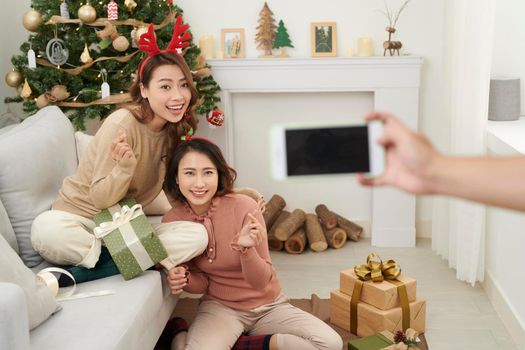 cute christmas girls showing presents to the cellphone friends.