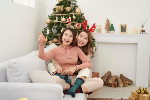 Friends cuddling on christmas day sitting on a couch in the living room at home