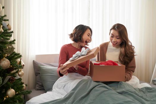 Image of surprised young women friends opening christmas present