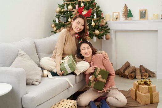 girl best friends celebrating christmas together. young ladies exchanging gifts at home and feel thankful hugging. love friendship on xmas concept.