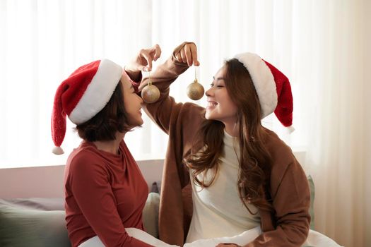 Two cute young woman in santa claus hat emotionally posing on new year photoshoot. 
