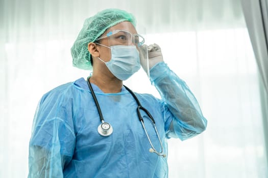 Asian doctor wearing face shield and PPE suit new normal to check patient protect safety infection Covid 19 Coronavirus outbreak at quarantine nursing hospital ward.