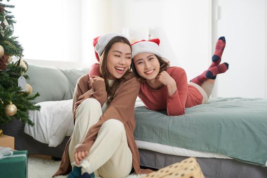 Two beautiful girls near the Christmas tree waiting for gifts