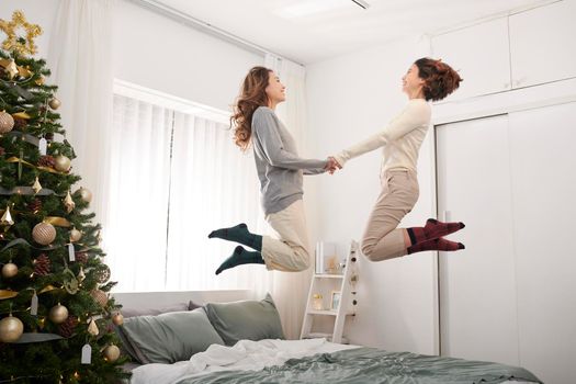 Happy kids jumping, having fun, playing on bed in bedroom enjoying of morning