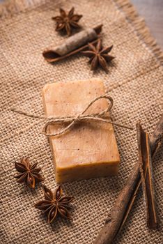 Handmade soap with cinnamon and anise star on wooden background.