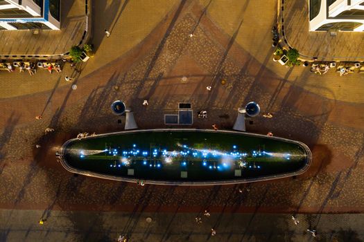 Top view of the city fountain in the new district of Minsk Mayak hot summer and vacationing people.People relax and walk near a large fountain in the city.Belarus.
