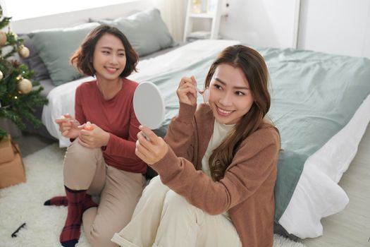 Two women massaging her face with rose quartz facial roller