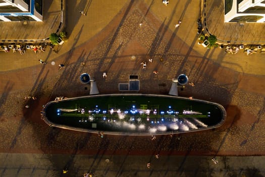 Top view of the city fountain in the new district of Minsk Mayak hot summer and vacationing people.People relax and walk near a large fountain in the city.Belarus.