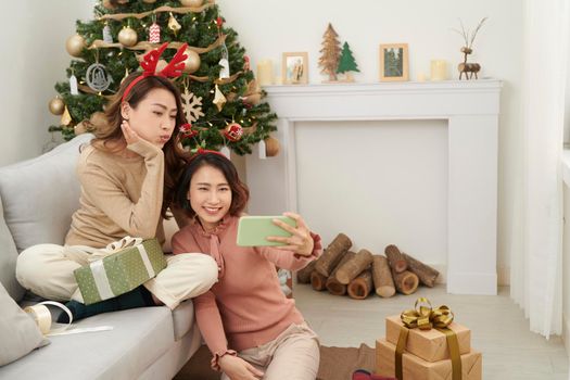 cute christmas girls showing presents to the cellphone friends.