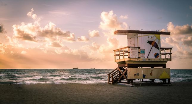 Miami South Beach sunrise with lifeguard tower and coastline with colorful cloud and blue sky, Florida, USA