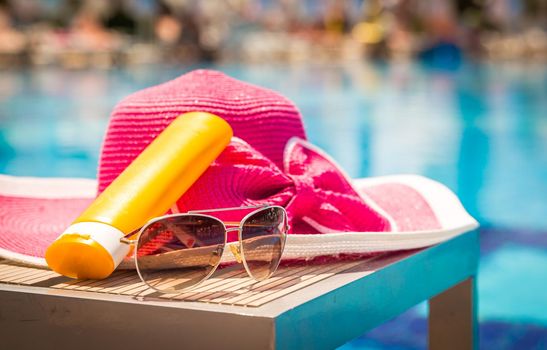 Bottles of suntan cream with sunglasses and hat on table