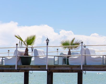 Pier on a sea with comfortable white armchairs