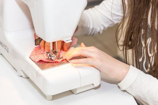 Little girl using sewing machine to make crafts