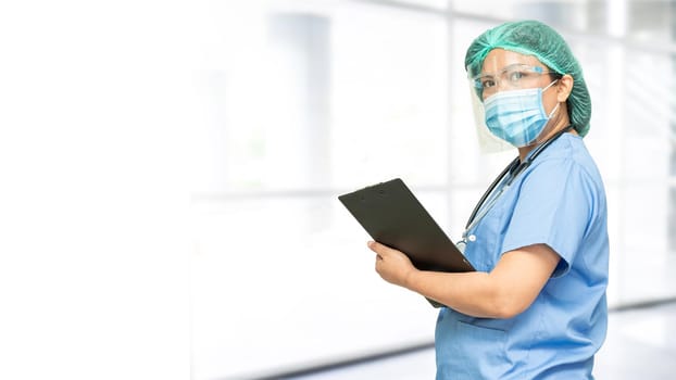 Asian doctor wearing face shield and PPE suit to check patient protect safety infection Covid-19 Coronavirus outbreak at quarantine nursing hospital ward, copy space