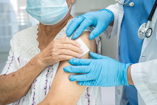 Elderly Asian senior woman wearing face mask getting covid-19 or coronavirus vaccine by doctor make injection.