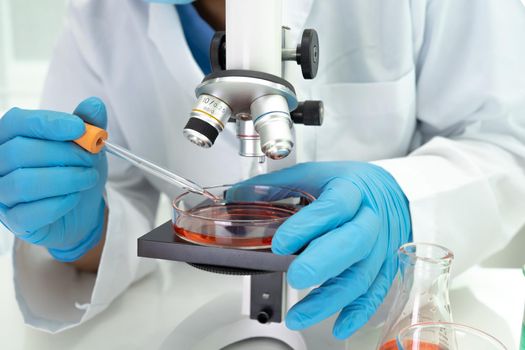 Asian scientist biochemist or microbiologist working research with a microscope in laboratory. For protect outbreak Coronavirus Covid19, bacteria and germs.