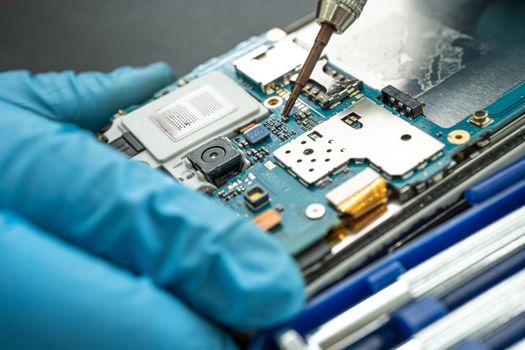 Technician repairing inside of mobile phone by soldering iron. Integrated Circuit. the concept of data, hardware, technology.