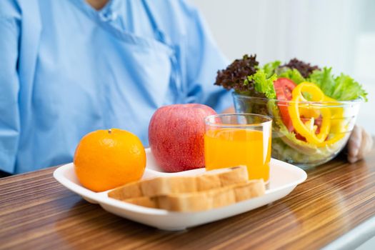 Asian senior or elderly old lady woman patient eating breakfast vegetable healthy food with hope and happy while sitting and hungry on bed in hospital.