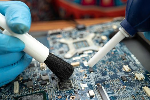 Technician use brush and air blower ball to clean dust in circuit board computer. Repair upgrade and maintenance technology.