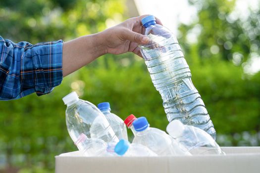 Asian woman volunteer carry water plastic bottles into garbage box trash in park, recycle waste environment ecology concept.