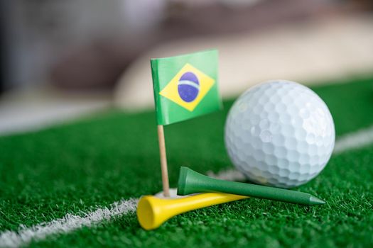 Golf ball with Brazil flag and tee on green lawn or grass is most popular sport in the world.