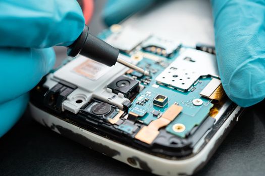 Technician repairing inside of mobile phone by soldering iron. Integrated Circuit. the concept of data, hardware, technology.